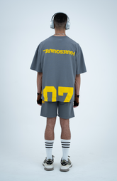 Model in the Haresquare Steey Grey T-shirt with a Yellow print, styled with Haresquare Grey shorts and designer sunglasses – unisex luxury sportswear from Ireland.